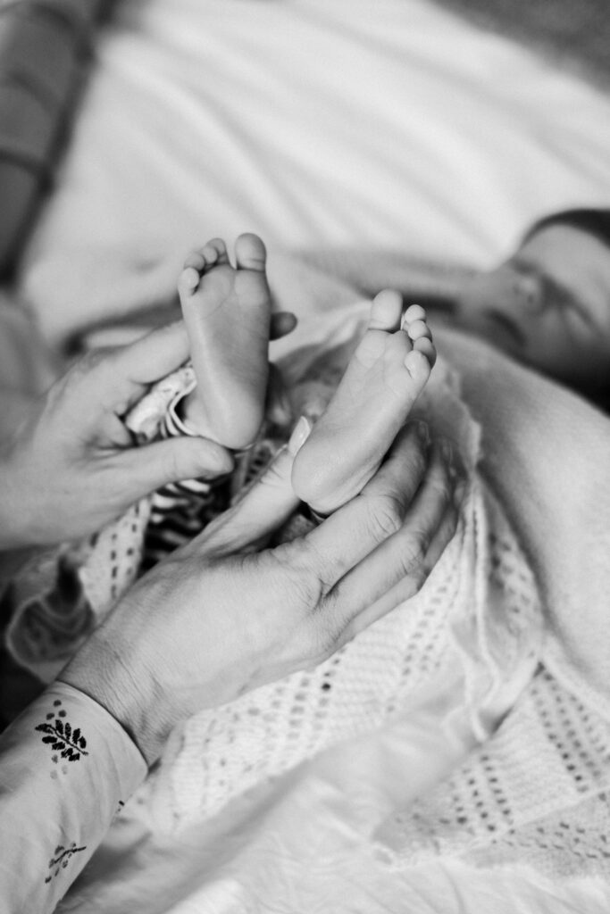 Mum holds her newborn son's tiny little feet while he sleeps at their home in London